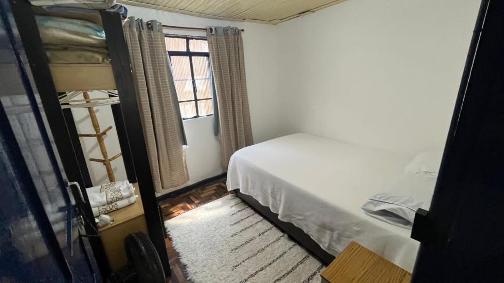 a small bedroom with a bed and a window at Quarto Britney in Ouro Preto