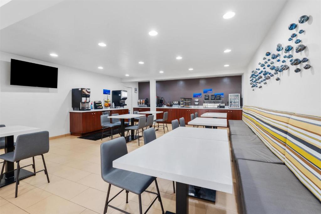 ein Restaurant mit weißen Tischen und Stühlen sowie einem TV in der Unterkunft Best Western San Diego&#47;Miramar Hotel in Miramar