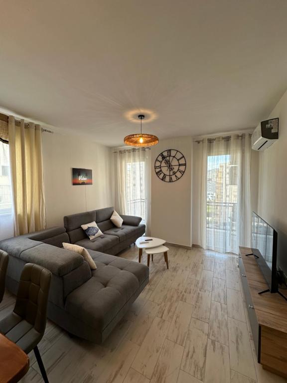 a living room with a couch and a clock on the wall at Casa Del Mar in Shëngjin