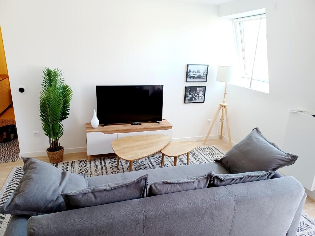 un salon avec un canapé et une télévision à écran plat dans l'établissement T2 neuf 2024, terrasse, parking, RER B et VAL à 2 pas, à Antony