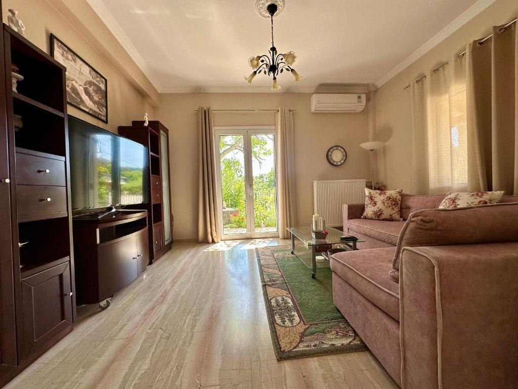 a living room with a couch and a tv at Mina's serene garden house in Kontokali