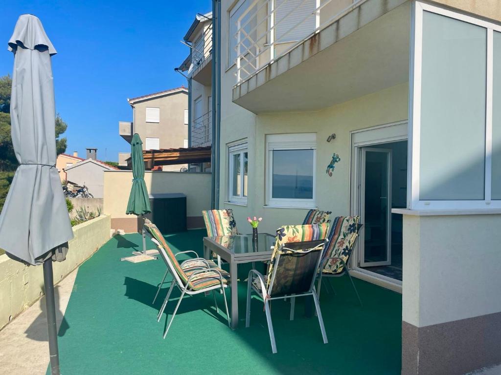 a patio with chairs and a table and an umbrella at Apartment Mandarina in Dugi Rat