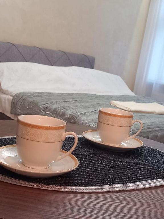 Hotel Apartament 8, two cups on plates on a table next to a bed at Apartament 8 in Toruń