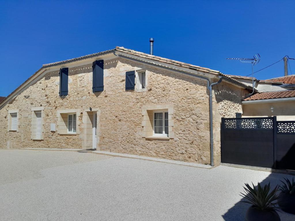 a stone house with blue shutters and a garage at Gîte 8 personnes in Sainte-Croix-du-Mont