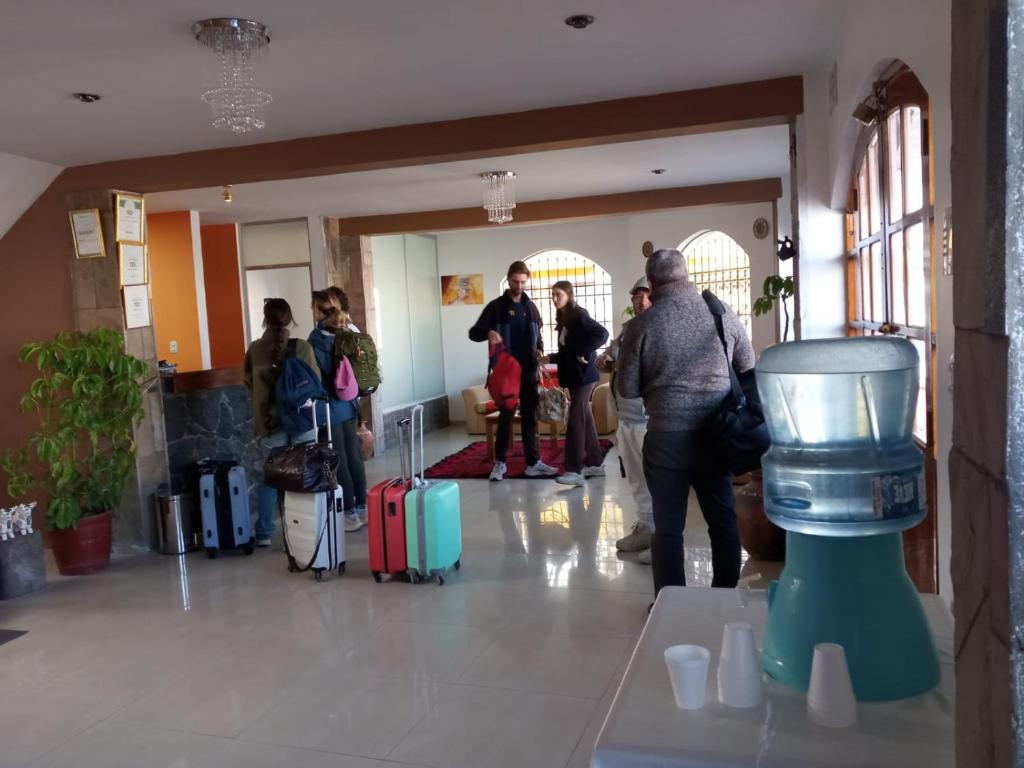 a group of people standing in a lobby with luggage at kuntur inn hotel in Puno