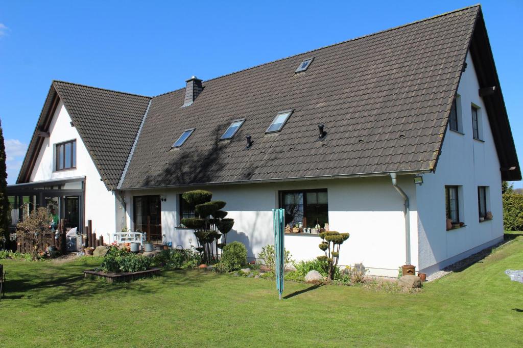ein großes weißes Haus mit schwarzem Dach in der Unterkunft Ferienwohnung Seeluft in Loissin