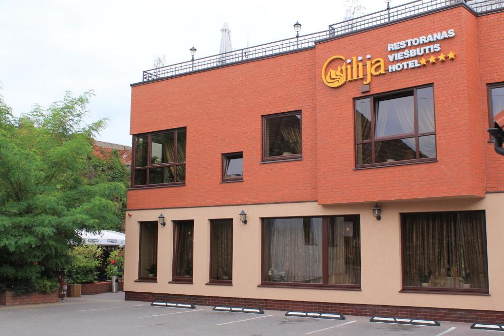 a red brick building with a sign on it at Gilija in Šilutė