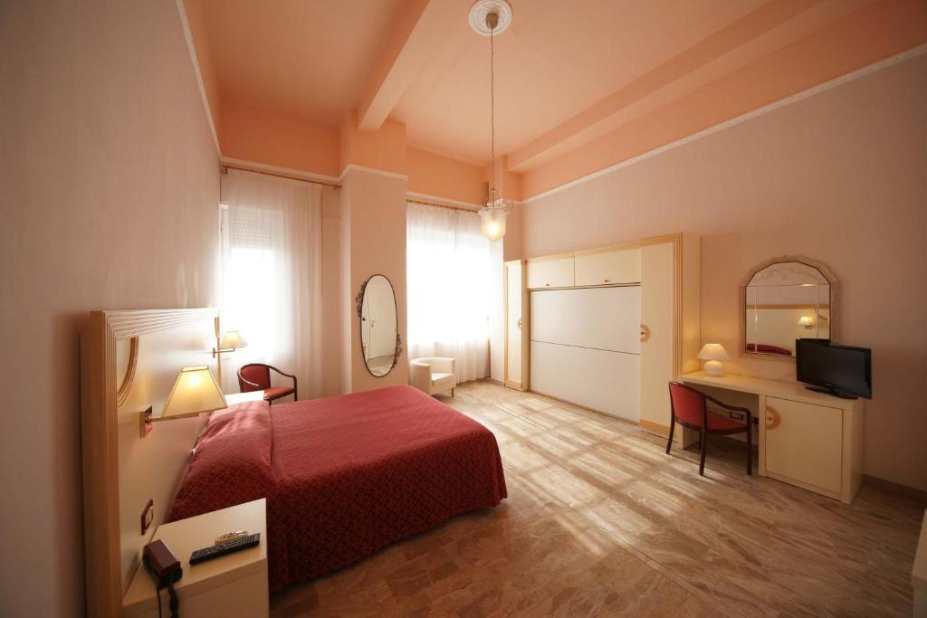 a bedroom with a bed and a desk and a television at Hotel Liberty in Viareggio