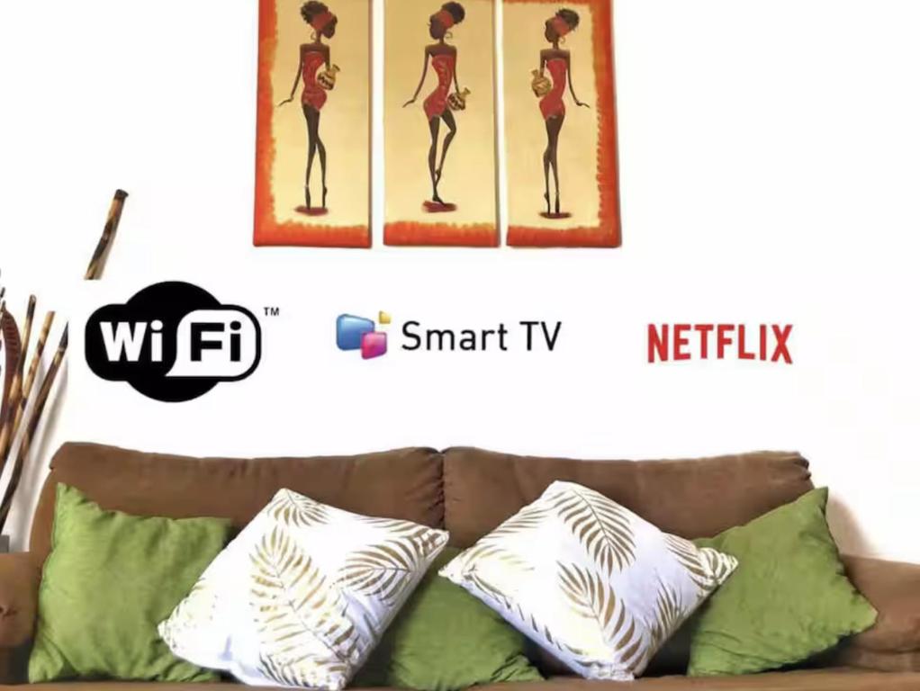 a couch with pillows and a picture of a woman at CASA DORADO B con AC y SMART TV Planta Baja in Mezcales
