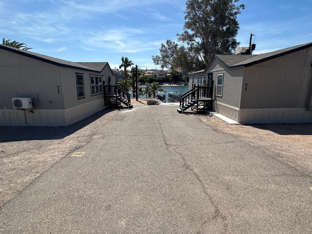 eine leere Straße zwischen zwei Gebäuden mit Bäumen und Wasser in der Unterkunft River Front Hideaway in Bullhead City
