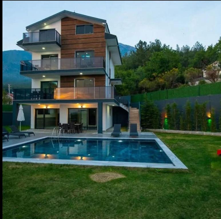 una casa con piscina delante de una casa en VILLA KoSAR, en Eskiömerler