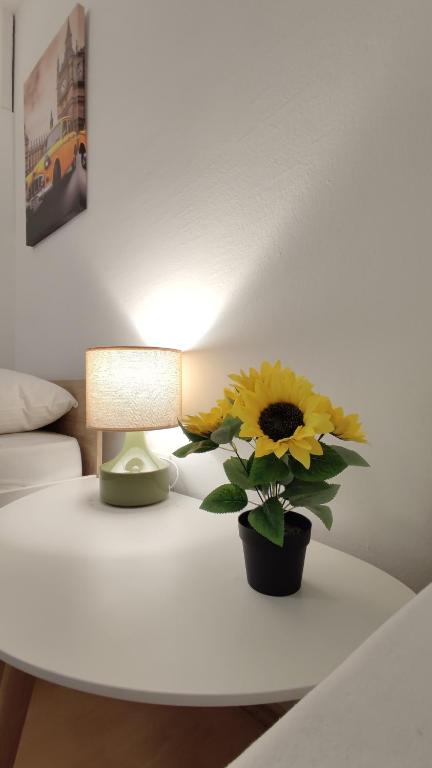 a table with a lamp and a vase with a sunflower on it at Apartmani Tarik in Mostar