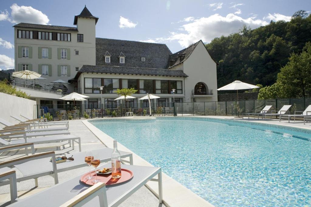 een hotelzwembad met stoelen en een gebouw bij Hôtel La Rivière in Entraygues-sur-Truyère
