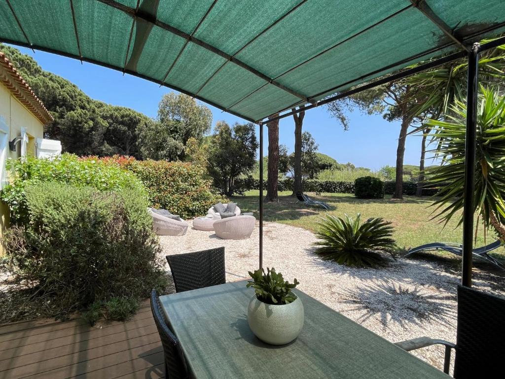 un patio avec une table et un parasol vert dans l'établissement Les Myrtes, à Saint-Tropez