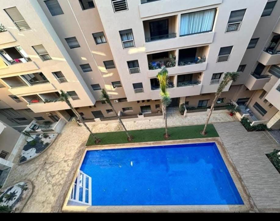 Un gran edificio de apartamentos con una gran piscina azul. en Superb apartment in the heart of city with POOL, en Marrakech