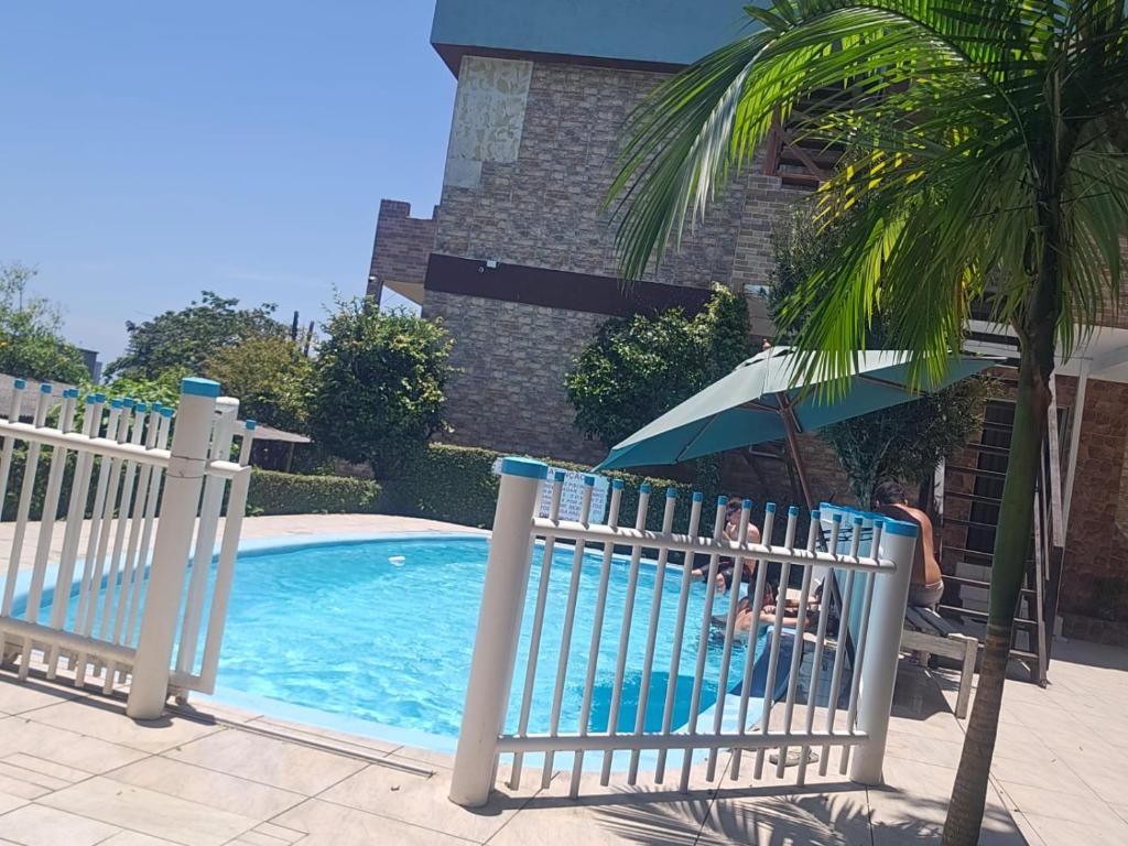 einen Zaun neben einem Pool mit einer Palme in der Unterkunft Pousada Martanha in Porto Belo