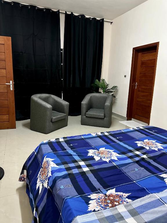 1 dormitorio con 2 sillas, 1 cama y cortinas en Simple Ecomomy Room in Cotonou, en Mama