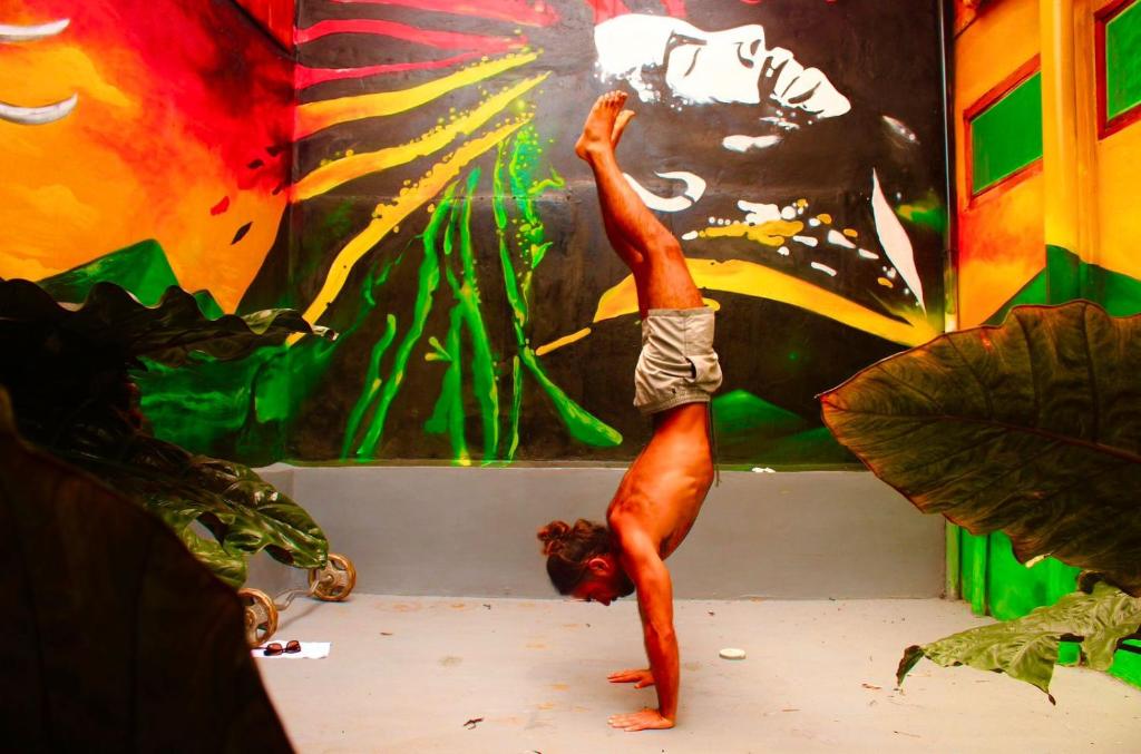 a man doing a handstand in front of a painting at Lazy Crab Hostel in Balgue
