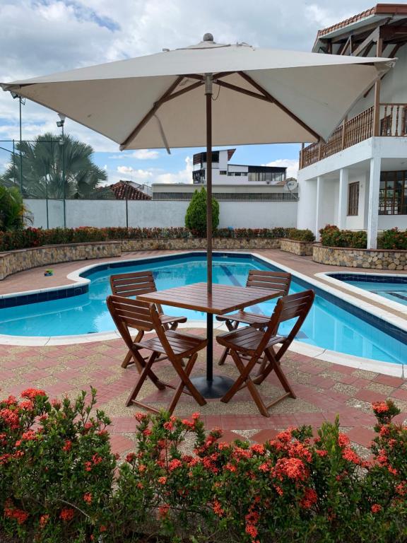 a table and two chairs under an umbrella next to a pool at Refugio de Paz Casa en Anapoima in Anapoima