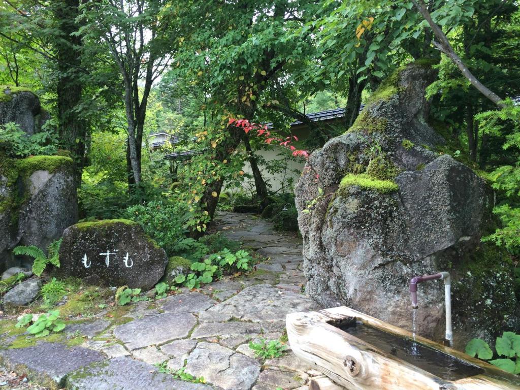 a garden with a stone path and a rock with moss at Mozumo (Adult Only) in Takayama