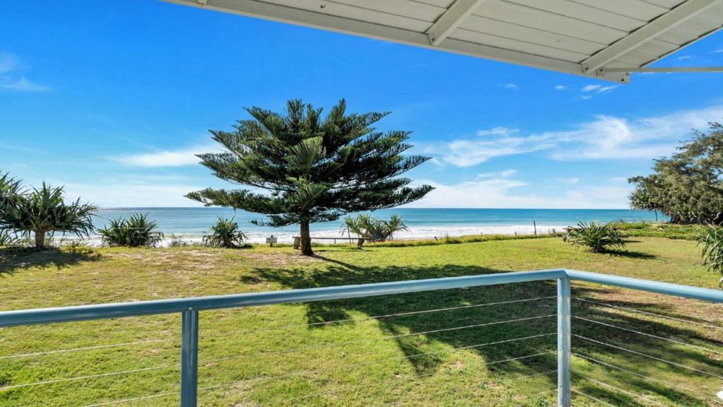 una vista della spiaggia dal balcone di una casa di Frangipani Cottage a Wooli