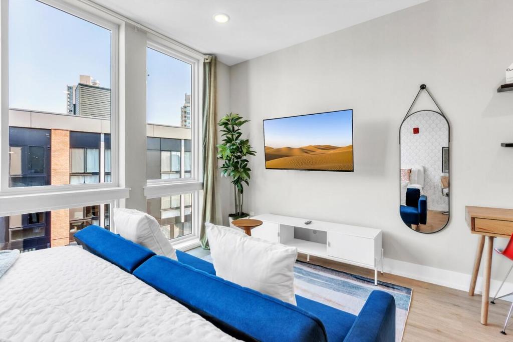 费城Floor To Ceiling Windows- Bridge Views - Studio的客厅配有蓝色的沙发和壁挂式冲浪板