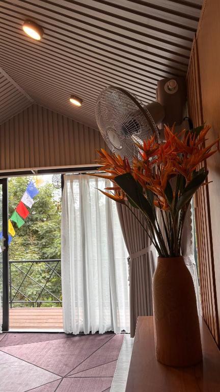 a vase with a fan and flowers in front of a window at Lilys Stone Garden Bungalow in Tram de Dak Mil