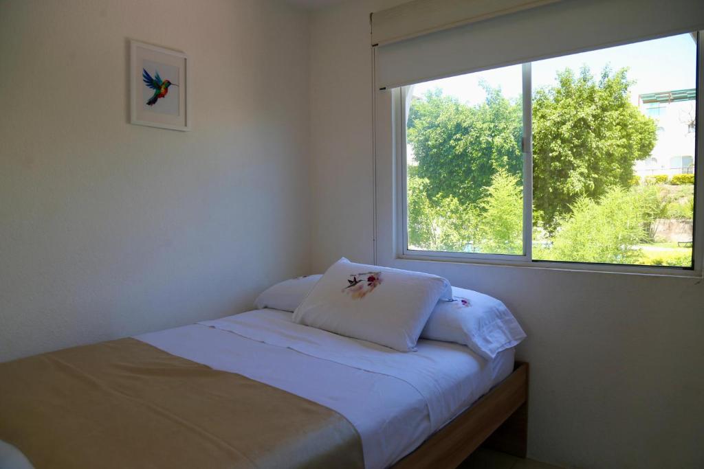 une chambre avec un lit avec une grande fenêtre dans l'établissement Casa Colibri Teques, à Tequesquitengo