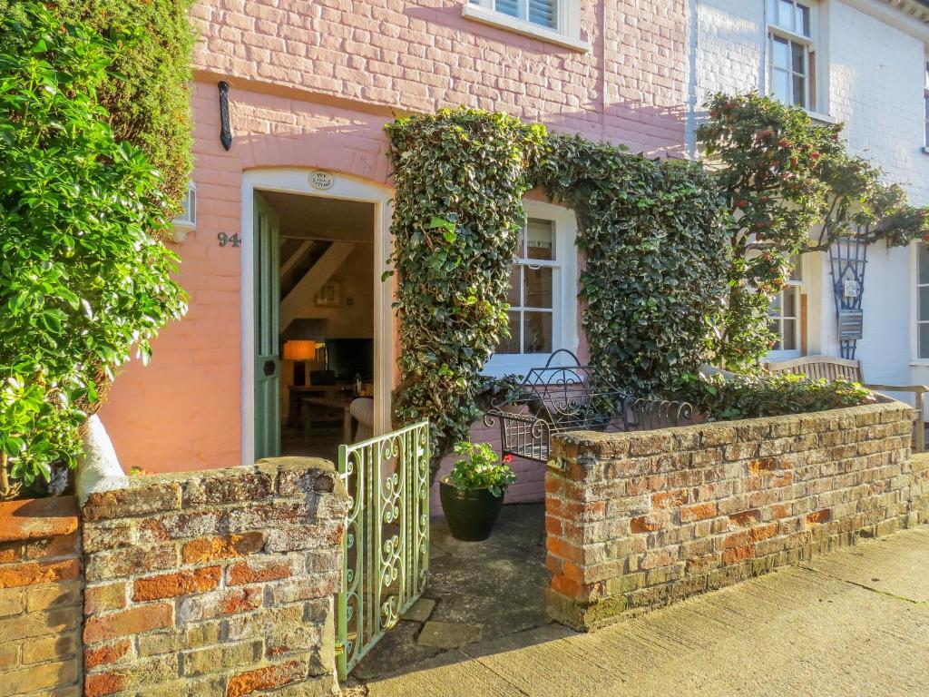 a pink brick house with a gate and ivy at Ivy Cottage in Aldeburgh