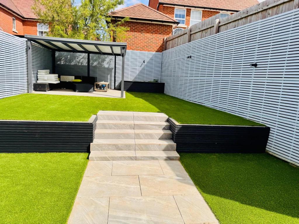 a backyard with a lawn and a concrete pathway at HIGH END Spacious 4 Bed House - Free parking in Greenhithe