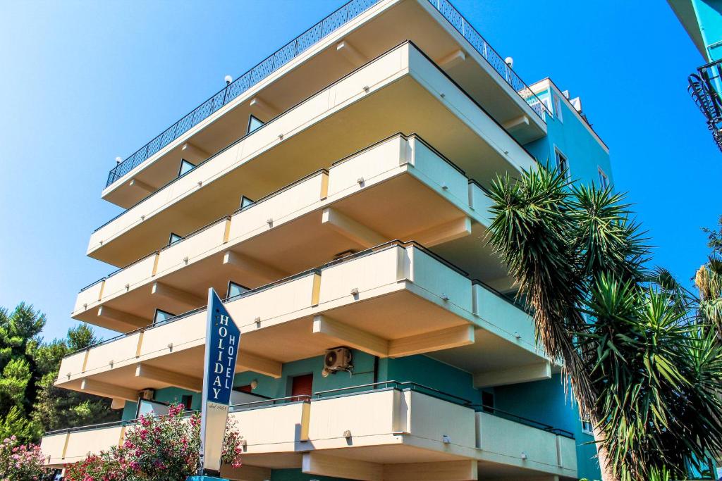 a building with a palm tree in front of it at Hotel Holiday in San Benedetto del Tronto