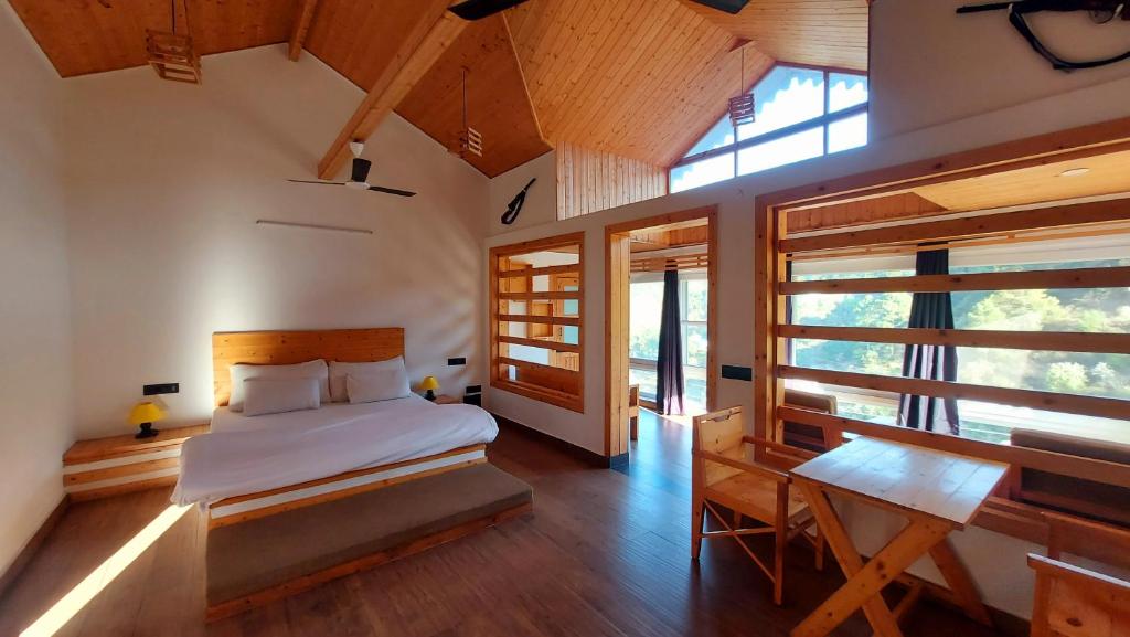 a bedroom with a bed and a desk and windows at DM Farms Morni Hills Panchkula in Morni