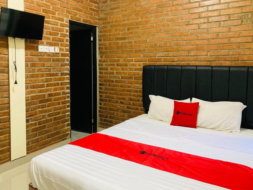 a bed in a room with a brick wall at RedDoorz near Jalan Malioboro Area in Ngabean