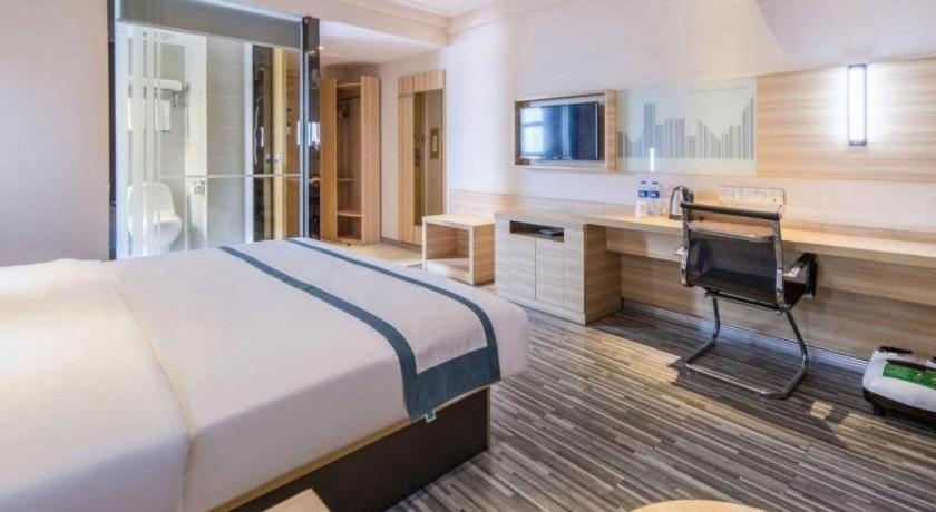 a hotel room with a large bed and a desk at City Comfort Inn Shantou Daxue Road in Shantou