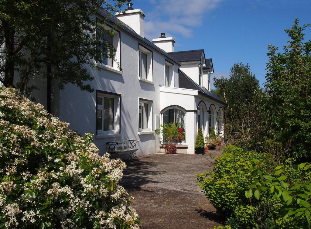a white house with flowers in front of it at Ballycommane House & Garden in Durrus