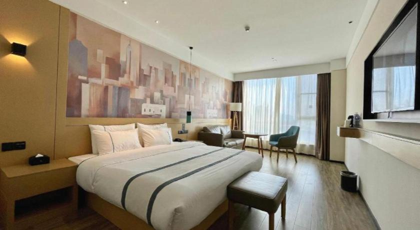 a bedroom with a large bed in a hotel room at City Comfort Inn Nantong Qidong Renmin Zhong Road Xingfudao in Huilongzhen
