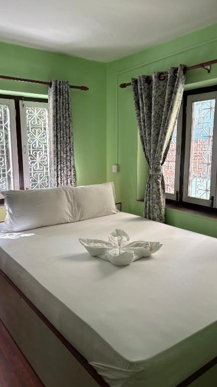 a bedroom with a large white bed with two windows at Trekking Lodge Nepal in Kathmandu