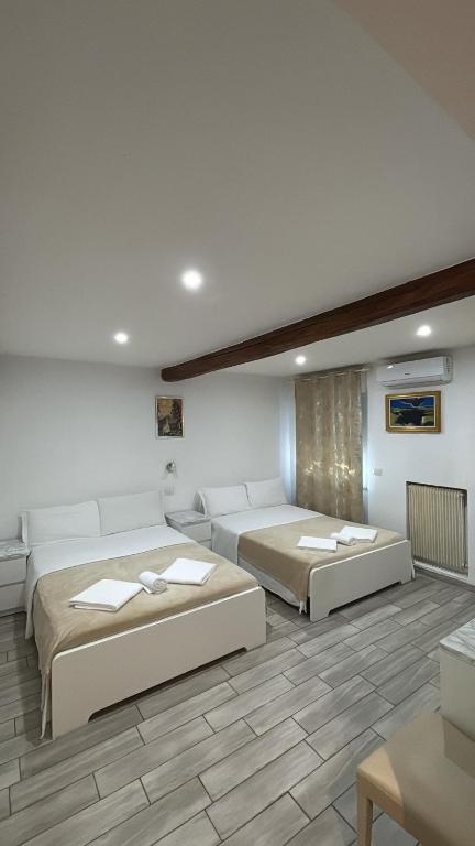 two beds in a large room with white walls at Sanella Rooms in Venice