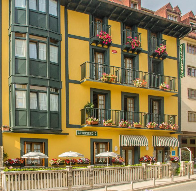 un edificio amarillo con balcones y sombrillas en Pension Getariano en Getaria