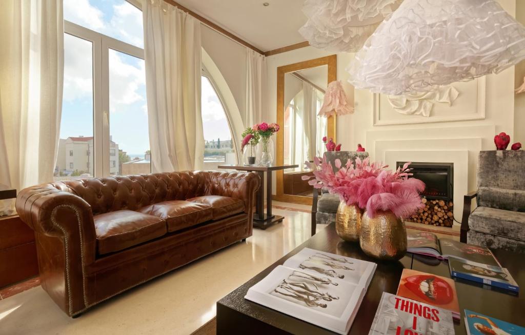 a living room with a brown leather couch and a table at Hotel Inglaterra - Charme & Boutique in Estoril