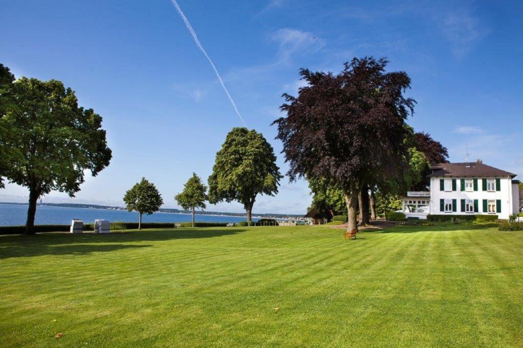 un campo de hierba con una casa y árboles en Seehof, en Sierksdorf