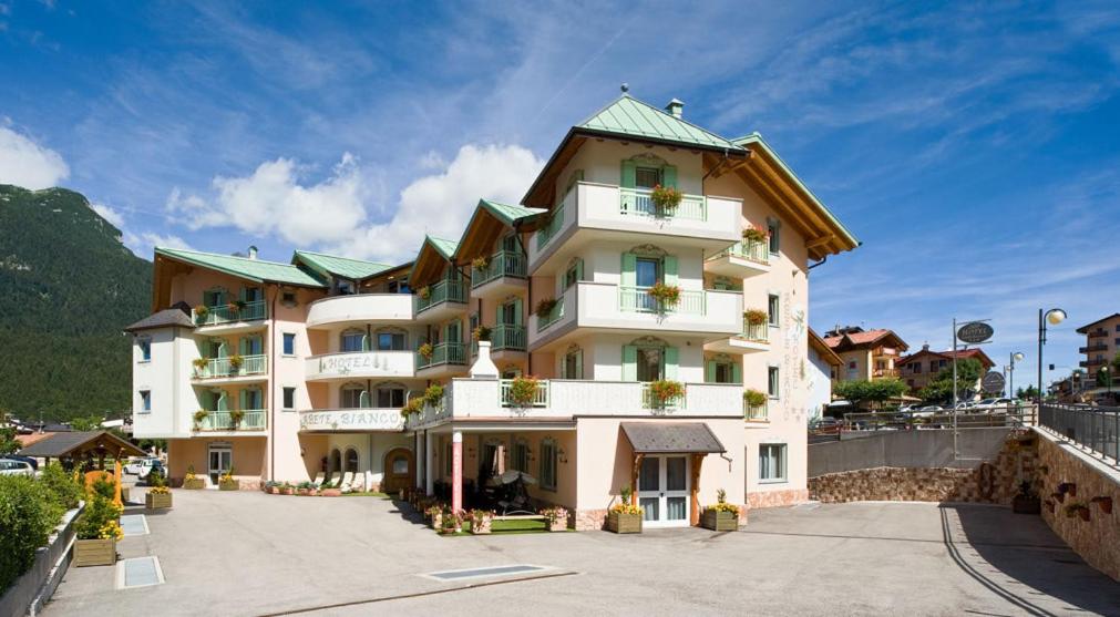 um grande edifício branco com um telhado verde em Hotel Abete Bianco em Andalo