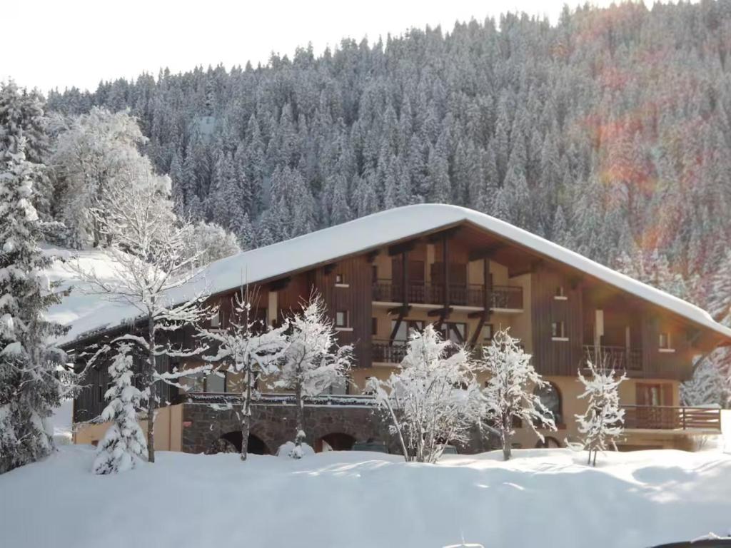 un bâtiment recouvert de neige avec des arbres en arrière-plan dans l'établissement Appartement 6 - Perce Neige, à Crest-Voland