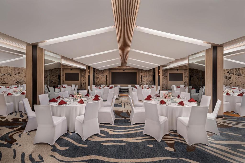 ハノイにあるDusit Le Palais Tu Hoa Hanoiの白いテーブルと椅子、スクリーンが備わる宴会場