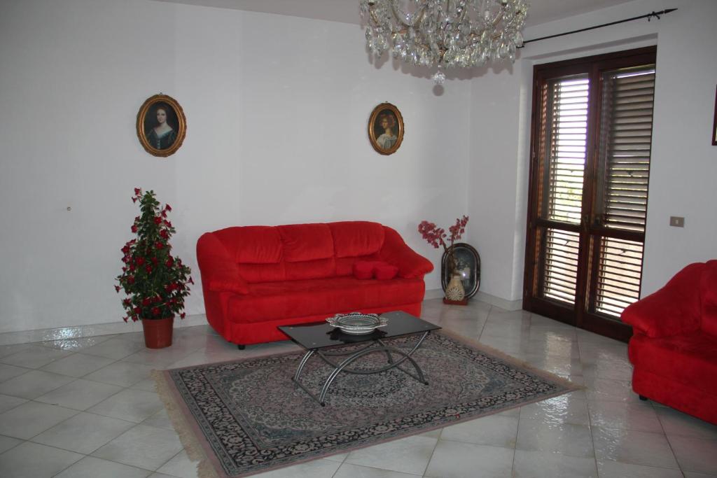 a living room with a red couch and a table at Gli Aranci Dell'Etna in Mascali