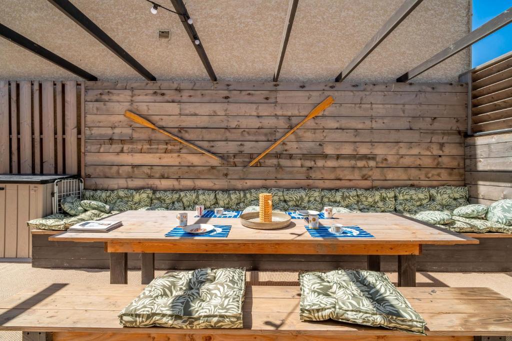 une table en bois et des bancs devant un mur dans l'établissement Passion Loft, à Gruissan