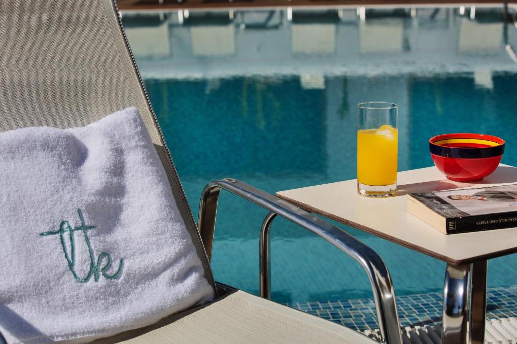 a glass of orange juice sitting on a table near a pool at Boutique Hotel El Tio Kiko in Agua Amarga