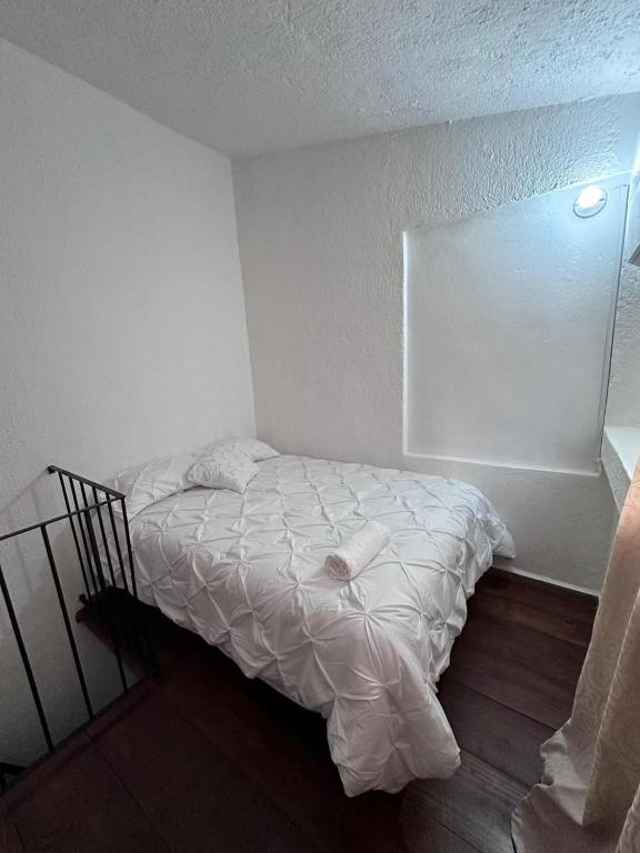 Un pequeño dormitorio con una cama blanca en una habitación en Departamento mini Huatulco, en Santa Cruz Huatulco