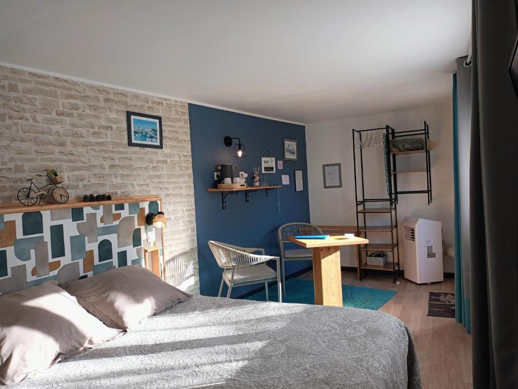 a bedroom with a bed and a table and a chair at Le Clos des Passiflores - Chambres d'Hôtes in Pons