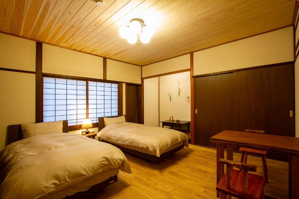 a bedroom with two beds and a desk and a table sidx sidx sidx at 女性専用お宿にこに in Izumo